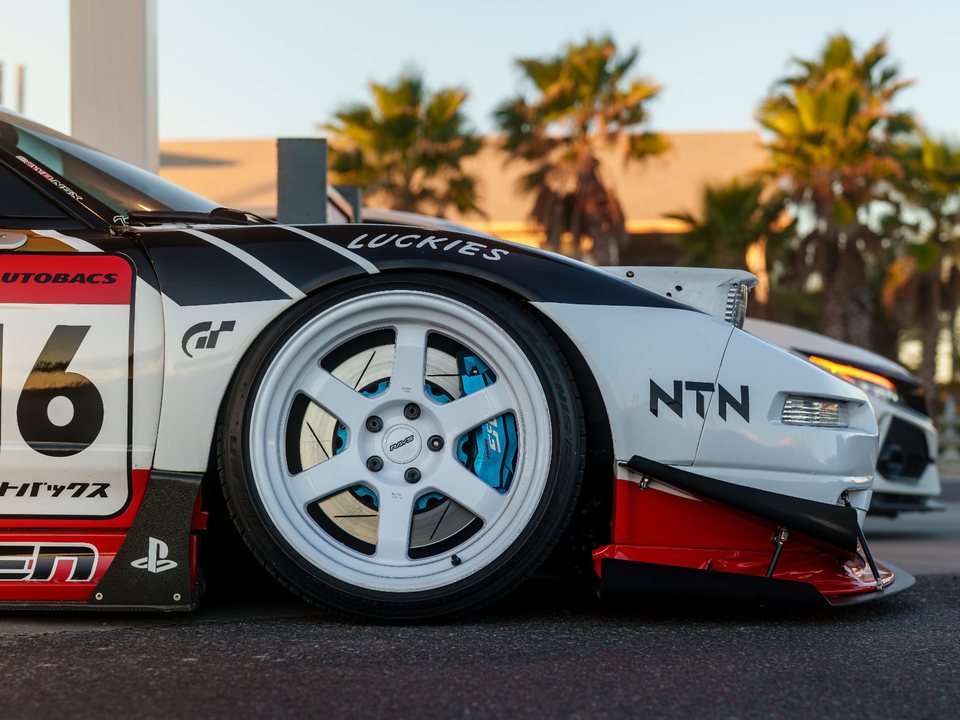 Lowered race-liveried sports car with a front splitter, canards and wide side skirts