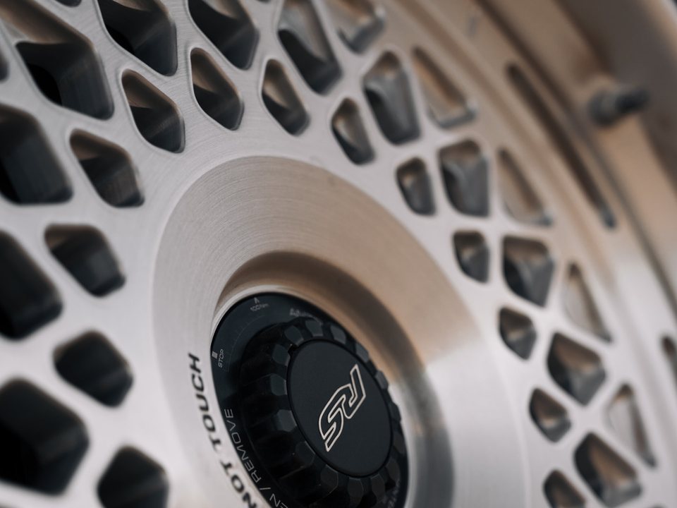 Close-up of a brushed multi-spoke mesh alloy wheel with a centre-lock cap