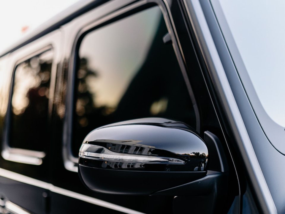 Tinted side windows and mirror on a glossy black luxury SUV
